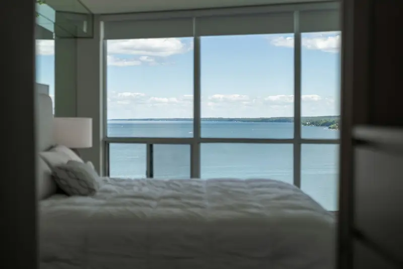 A bedroom with a wall of glass looking over open water